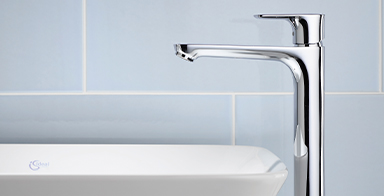 Photo d'une robinetterie Ideal Standard de profil surplombant un lavabo plan, carrelage bleu ciel en arrière-plan