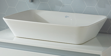 Photo d'un lavabo blanc Ideal Standard posé sur un meuble blanc, carrelage bleu ciel en arrière plan